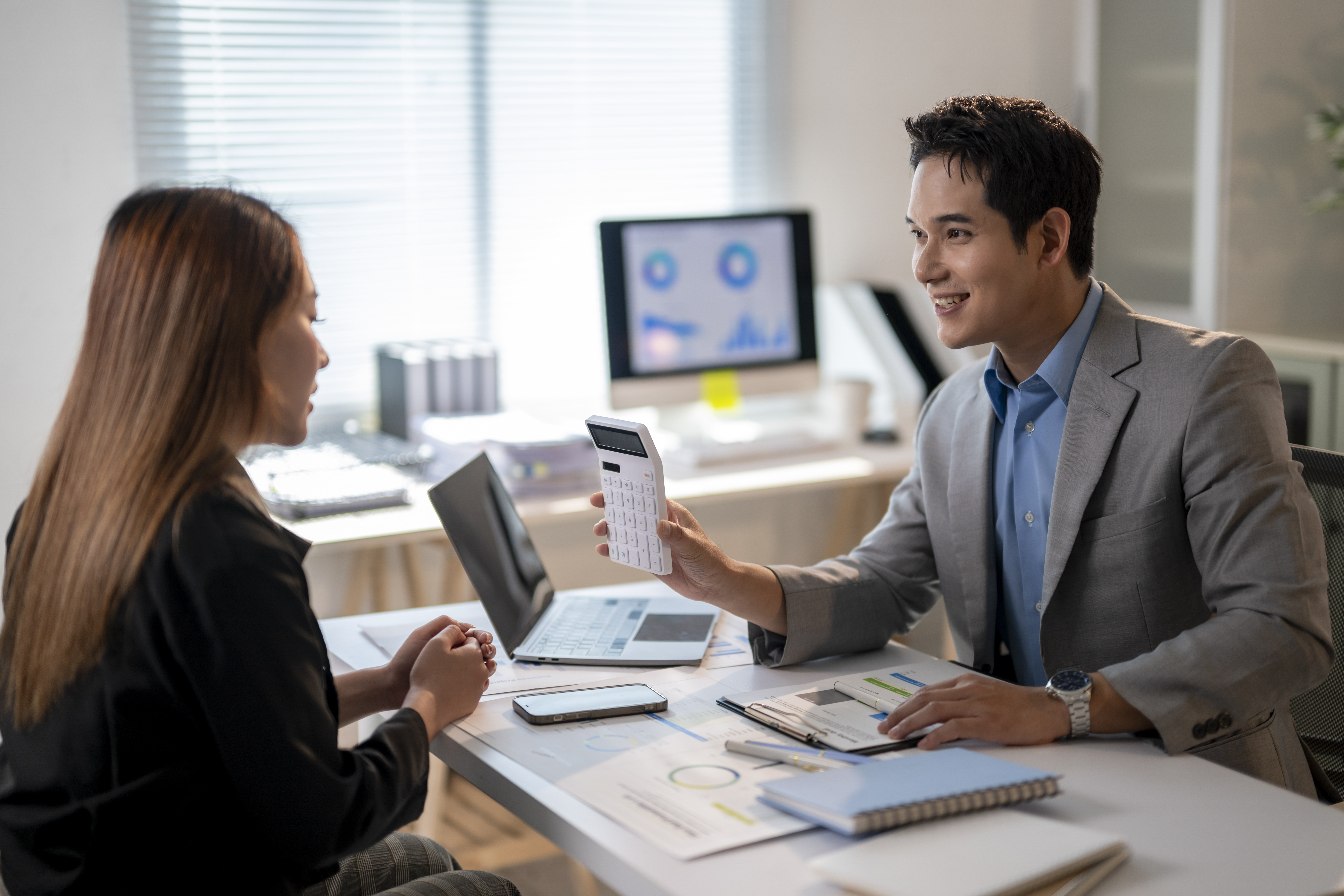 Financial advisor showing calculator to woman analyzing documents